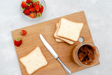 Sandwich toast bread with peanut butter, strawberry,nuts on wooden cutting board. kids childrens baby's sweet dessert, healthy breakfast,lunch, food art on gray background,top view,flatlay