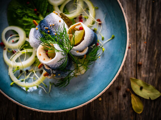 Marinated herring fillets with pickled cucumber, dill and  onion on wooden table

