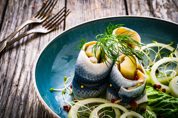 Marinated herring fillets with pickled cucumber, dill and  onion on wooden table
