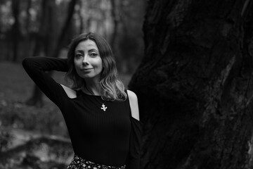 Beautiful young woman near an old tree in black and white