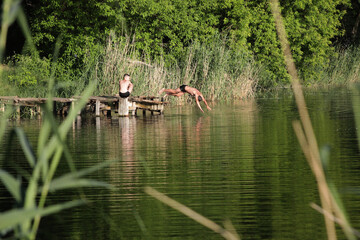 The boys jump into the water from the bridge
