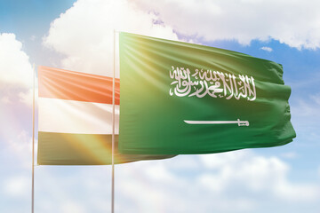Sunny blue sky and flags of saudi arabia and hungary