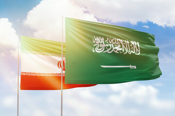 Sunny blue sky and flags of saudi arabia and iran