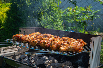 Outdoor grilling, barbecue. Grilling sausages and chicken in the open air.
