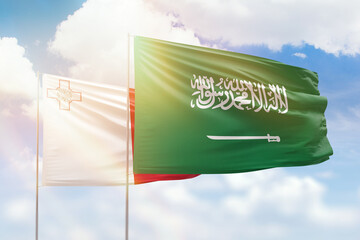 Sunny blue sky and flags of saudi arabia and malta