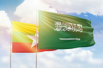 Sunny blue sky and flags of saudi arabia and myanmar