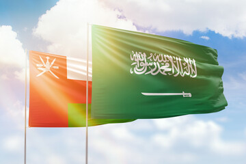 Sunny blue sky and flags of saudi arabia and oman