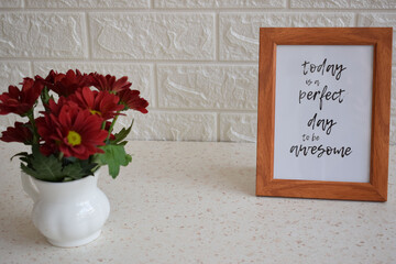 Motivational quote on a white background and a vase of flowers 