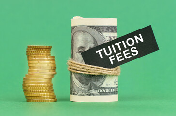 On a green surface are coins and dollars in a bundle. On the dollar sign with the inscription - Tuition Fees