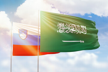 Sunny blue sky and flags of saudi arabia and slovenia