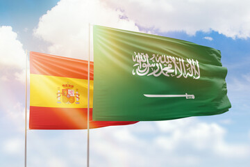 Sunny blue sky and flags of saudi arabia and spain