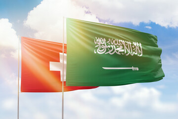 Sunny blue sky and flags of saudi arabia and switzerland