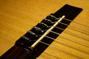 Macro photo of a guitar bridge with tail pieces of a nylon strings. Fully sharp picture. Background picture.