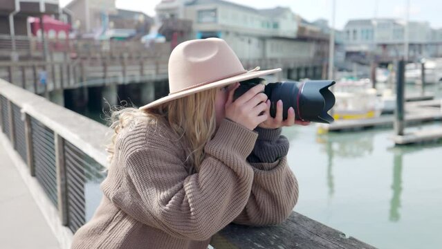 Close-up view of a female photographer taking pictures of city bay. Woman traveling with a camera around coastal town. High quality 4k footage