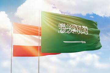 Sunny blue sky and flags of saudi arabia and austria