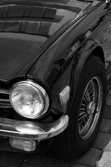 Scheinwerfer eines britischen Roadster und Sportwagen der Siebziger Jahre mit Chromspeichenrad vor...