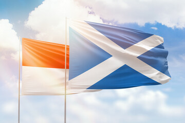 Sunny blue sky and flags of scotland and indonesia