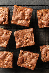 Chocolate brownies close up on baking rack on dark background, top view
