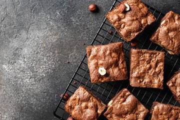 Chocolate brownies with nuts on baking rack on dark background, top view, text space