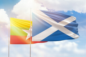 Sunny blue sky and flags of scotland and myanmar