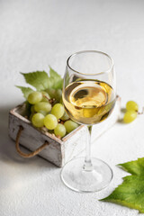 White wine still life with grapes in rustic wooden box on white background with text space