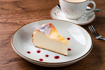 Cheesecake slice, New York style classical cheese cake on wooden background. Slice of tasty cake on white plate served