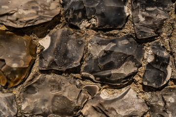Closeup on various flint stones used in UK as a building material in architecture. Flint is the hardest of building stones, used by the Romans for castle walls and by medieval masons for churches
