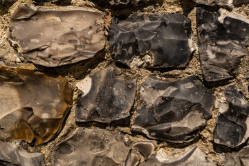 Closeup on various flint stones used in UK as a building material in architecture. Flint is the hardest of building stones, used by the Romans for castle walls and by medieval masons for churches
