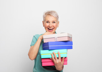 Elderly woman 60s holding present boxex with gifts isolated on white grey background
