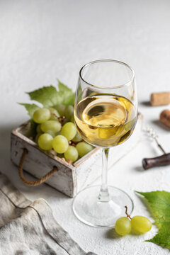 White wine still life with grapes in wooden box, corkscrew and linen napkin on white background
