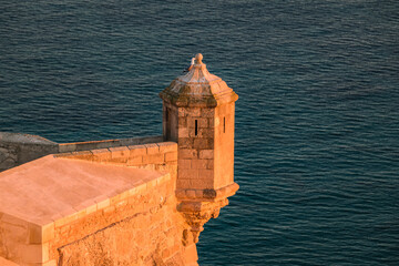 Tower of Santa Barbara castle against sea at sunset, Alicante, Spain.
