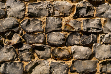 Closeup on various flint stones used in UK as a building material in architecture. Flint is the hardest of building stones, used by the Romans for castle walls and by medieval masons for churches