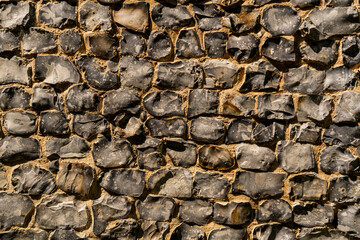 View of a big wall made of flint stones, building material in architecture used in UK. Flint is the hardest of building stones, used by the Romans for castle walls and by medieval masons for churches