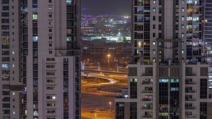 The second pedestrian bridge of Dubai water canal suspended by an oval arch aerial night timelapse from Business bay district.