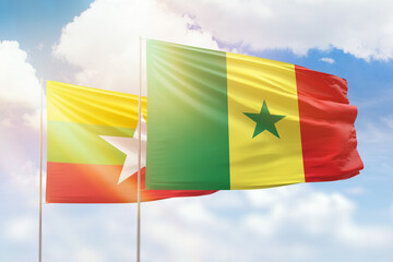 Sunny blue sky and flags of senegal and myanmar