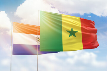 Sunny blue sky and flags of senegal and paraguay