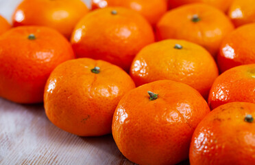 Heap of fresh whole clementines on wooden background. Concept of health benefits of citrus © JackF
