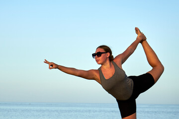 Young healthy woman practicing and workout yoga on the beach at sunset, benefits of natural...