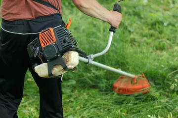 Person mowing the grass with a brushcutter - 511968280