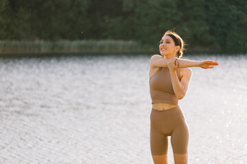 Happy woman practicing yoga on the outdoors by the river