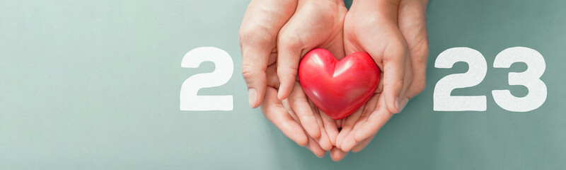 2023 with hands holding Red heart , Happy New Year for heart health insurance, donation and medical...