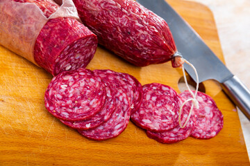 Popular Spanish Salchichon cured sausage, cut into pieces on the table. Close-up image