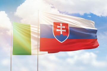 Sunny blue sky and flags of slovakia and italy