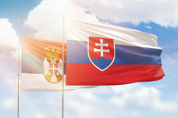 Sunny blue sky and flags of slovakia and serbia