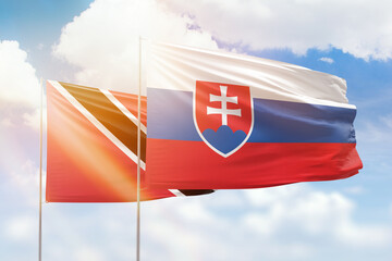 Sunny blue sky and flags of slovakia and trinidad and tobago
