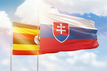 Sunny blue sky and flags of slovakia and uganda