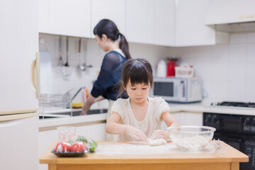 料理を手伝う女の子とお母さん