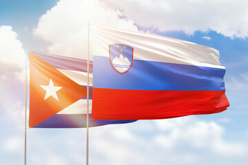 Sunny blue sky and flags of slovenia and cuba