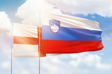 Sunny blue sky and flags of slovenia and england