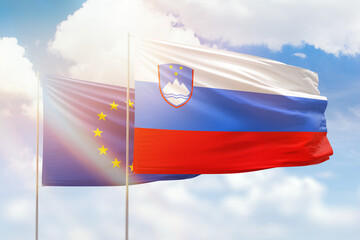 Sunny blue sky and flags of slovenia and european union